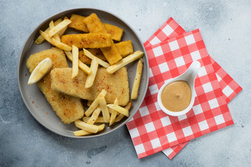 Fish and chips served in a grey plate, flatlay over light-blue stone background, horizontal shot