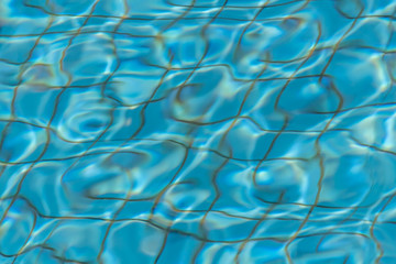 Beautiful texture of water with sun lights in a pool on the blue background of texture of small square ceramic tile