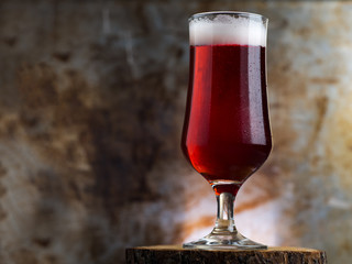 A glass of red ale on a dark metal background