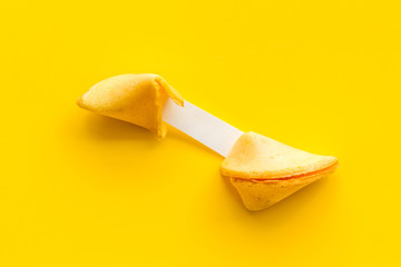 Fortune cookie - broken piece with prediction inside - on yellow background copy space