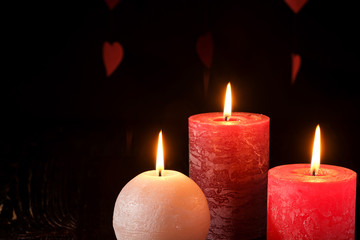 Three wax flame candlelight in dark romantic light on hearts background, love dating, Valentine's day, selective focus