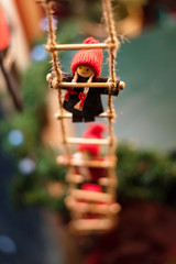 Little cute rag doll climbing the rope ladder. Little gnome dolls in red hats sitting on Christmas stairs. Christmas decoration. Selective focus