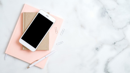 Home office desk workspace with smartphone screen mockup, pink notepad, pen on marble background....