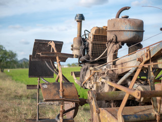 Old and rusty two wheeled tractor or power tiller with paddy field in the background