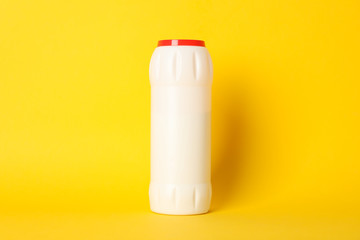 Bottle with detergent powder on yellow background, space for text