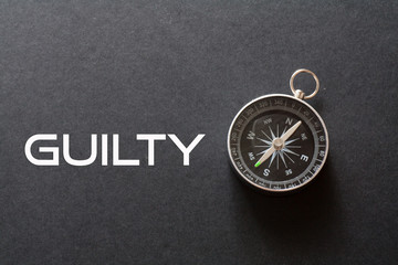 Guilty word written on black background with compass