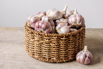 Garlic in a wicker basket on a wooden table background. Copy, empty space for text