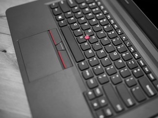 Black laptop keyboard trackpoint red dot cap and touchpad with buttons close up view