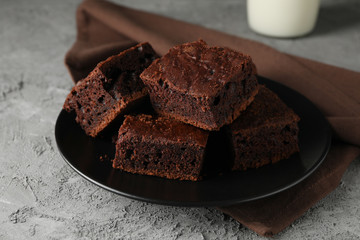 Plate with chocolate cake slices and bottle of milk on grey table, close up