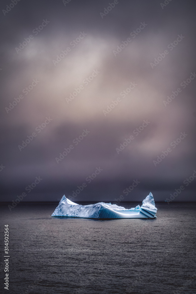 Wall mural Dramatic image of an iceberg floating in dark