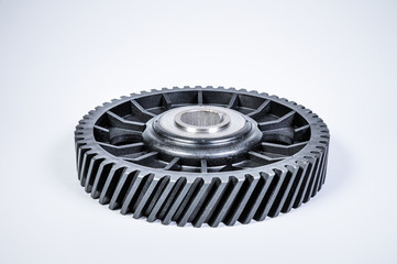 Black polymer gear camshaft with metal base. New spare part for an internal combustion engine on a gray background