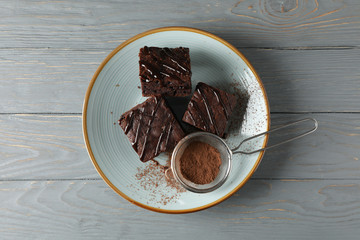 Plate with chocolate cake slices and strainer with powder on wooden background, top viewPlate with chocolate cake slices and strainer with powder on wooden background, top view