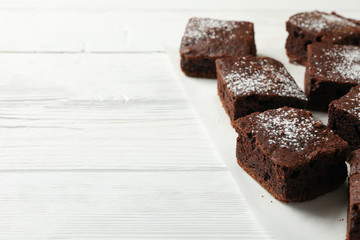 Chocolate cake slices on white wooden background, space for text
