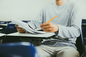 high school,university student study.hands holding pencil writing paper answer sheet.sitting lecture chair taking final exam attending in examination classroom.concept scholarship for education abroad