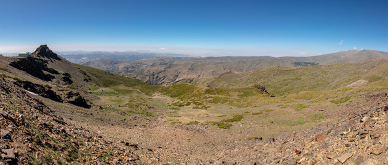 mountain range's panoramic view from the top of the mountains. Stones and shrubs.