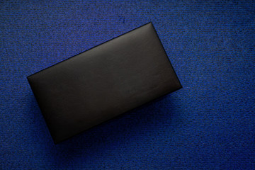 Big black box on blue textured background. Top flat lay view. Luxury gift chest leather covered