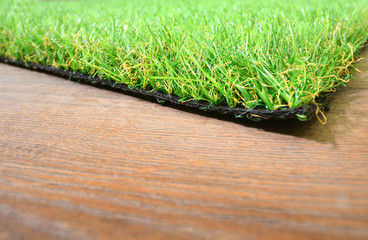 Artificial grass lie on the wooden background