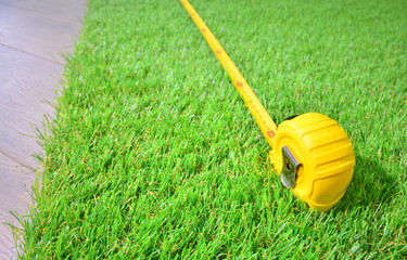 Artificial turf and measure tape lie on the laminate floor