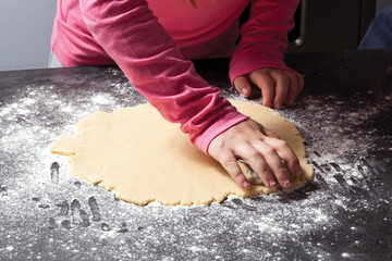 Close up of kid cutting out cookie shapes from cookie dough.