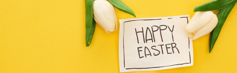 top view of greeting card with happy Easter lettering and tulips on yellow colorful background, panoramic shot