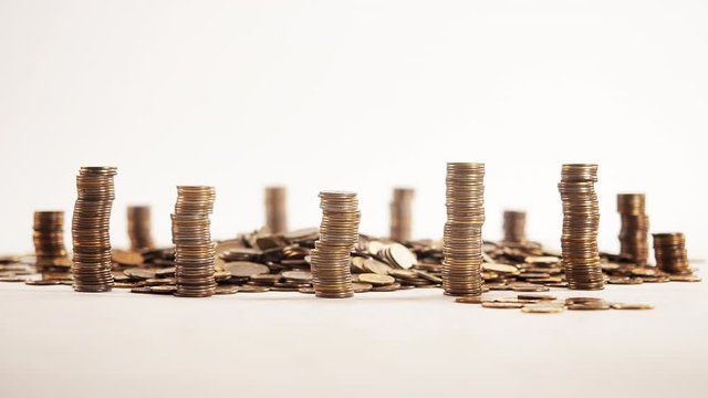 The concept of money. Columns of gold coins in the form of skyscrapers or Stonehenge. Close-up hands make up stacks of coins. Smoke. Garland.