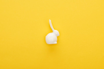 Top view of white Easter bunny on colorful yellow background