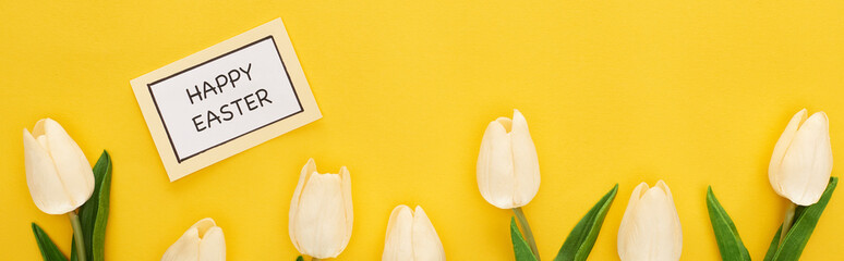 top view of tulips, greeting card with happy Easter lettering on yellow colorful background, panoramic shot