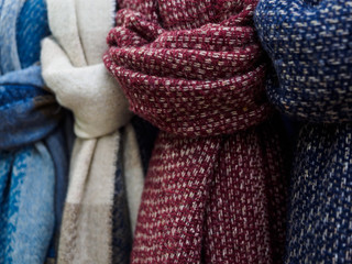 Wool scarves hang in the shop window. Colorful scarves tied in a knot