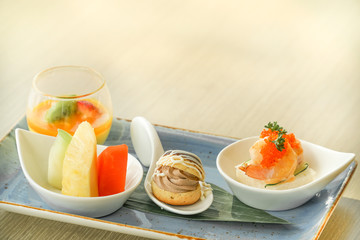 A set of Italian and Japanese appetizers: sushi and cheese, served with olives. Wooden background with copy space