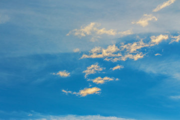 golden clouds on a blue sky at sunset. beautiful nature background. wonderful atmosphere scenery in...