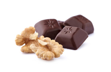 Closeup shot of cut dark chocolate with walnuts on white background.
