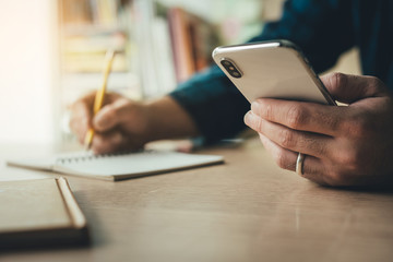 hand holding using texting cell phone and typing computer.businessman at workplace Thinking investment plan.chatting contact Investor.searching for information use internet.connecting people concept