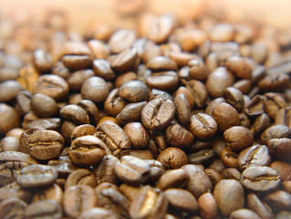Whole coffee beans on wooden background. Fresh coffee beans ready for the grinder. Selective focus and close up.