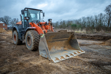 on a large construction site, excavators are used to remove topsoil so that a foundation for a large factory building can be built