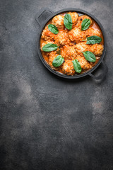 Meatballs in tomato sauce with bazil leaf in a frying pan on dark background. Top view. Copy space.