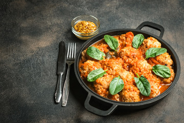 Meatballs in tomato sauce with bazil leaf in a frying pan on dark background. Top view.