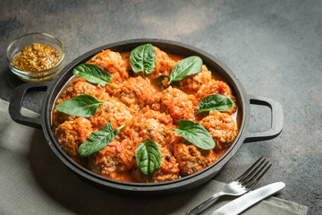 Meatballs in tomato sauce with bazil leaf in a frying pan on dark background. Top view.