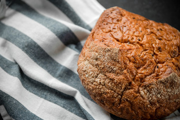 round loaf of rye bread on a grey striped towel