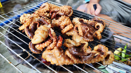 Delicious grilled octopus on metal grill seafood bbq with chili sauce spring onion tentacles calamari tasty marinated Vietnamese street food Asian cuisine