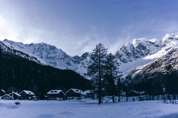 Fototapeta na wymiar The town of Macugnaga, in the Italian Alps, with its typical houses, the snow and Monte Rosa - December 2019.