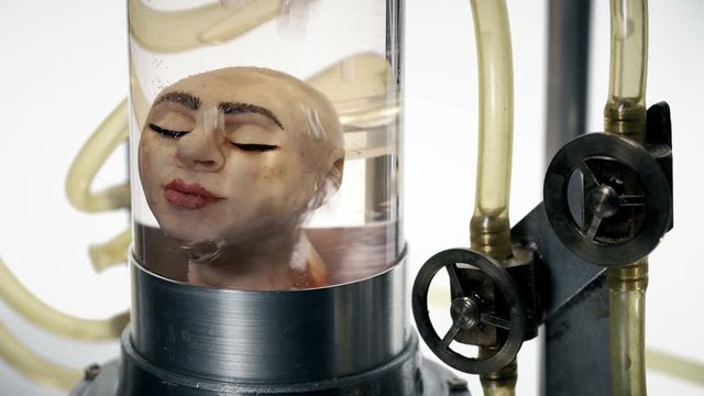 head of a woman without a body in a cylindrical glass vessel (flask), in a liquid with air supply (bubbles), similar to a laboratory for experiments, close-up