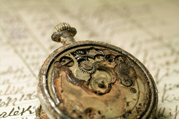 Fototapeta na wymiar Rusted antique pocket watch on an old notebook