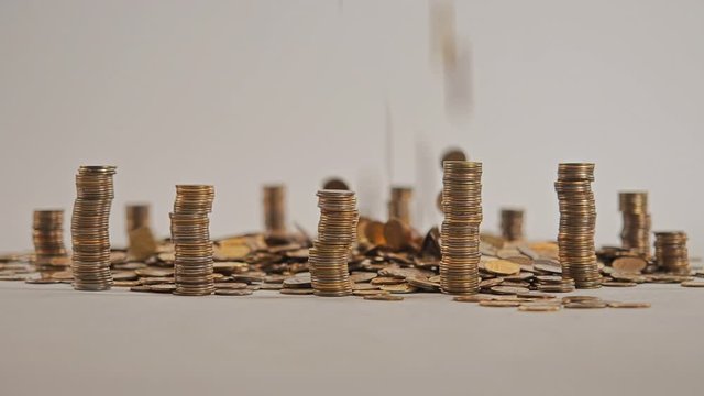 The concept of money. Columns of gold coins in the form of skyscrapers or Stonehenge. Close-up hands make up stacks of coins. Smoke. Garland.