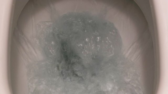 Toilet Flushed Top View. Close-up view of a Water flushing down into the toilet bowl in restroom