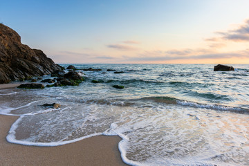 sunrise on the beach. beautiful summer scenery. rocks on the sand. calm waves on the water. clouds...