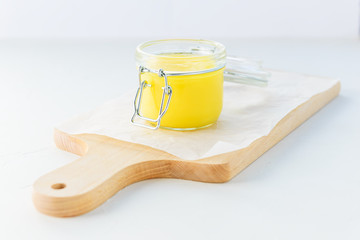 Ghee butter in a jar on a wooden board.