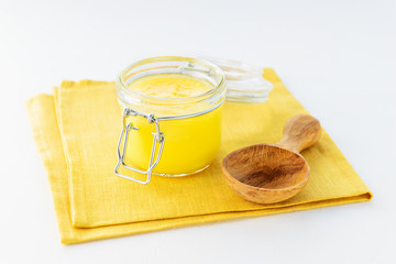 Ghee butter in a bowl with a spoon on a yellow napkin.