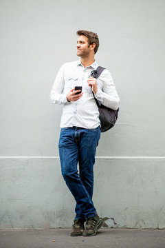 Full Body Handsome Man With Mobile Phone And Bag By Gray Wall