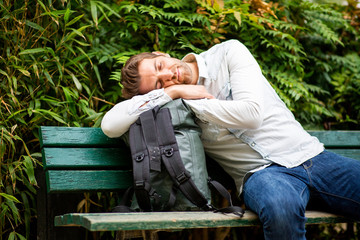 middle age man with bag sleeping on park bench
