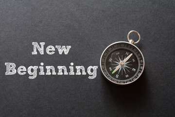 New Beginning written with Compass on black paper background